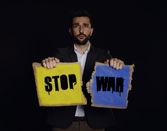 Unhappy man holding sign with phrase Stop War on black background