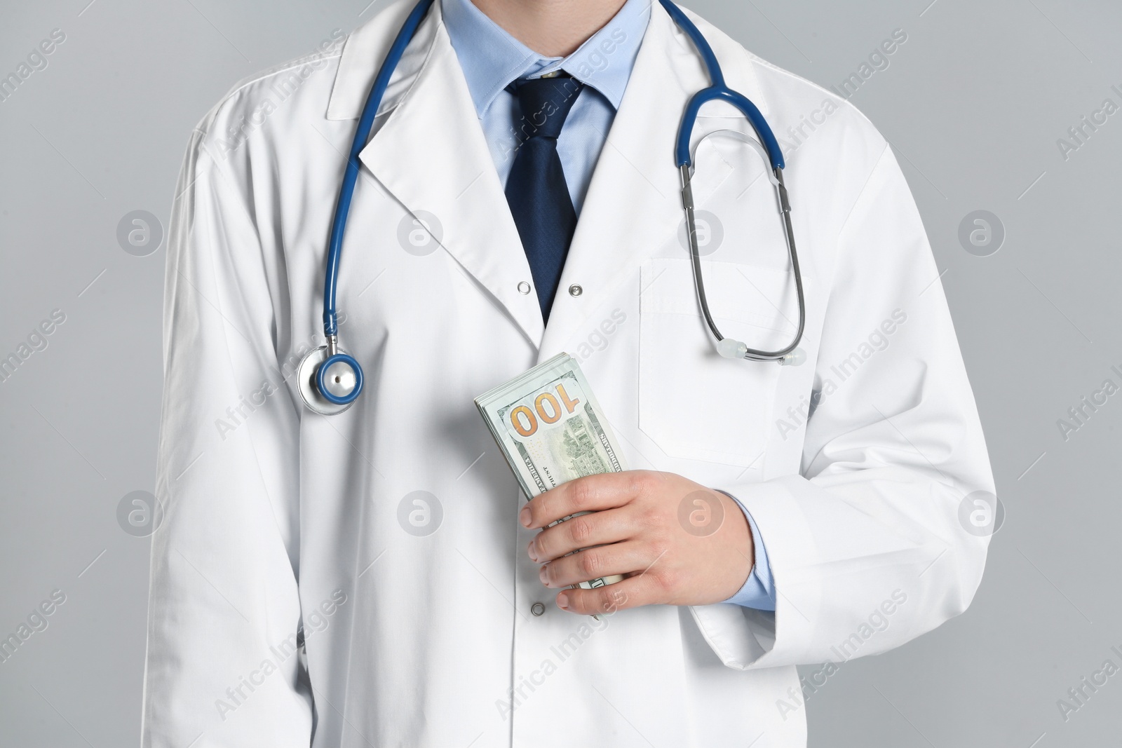 Photo of Doctor with bribe on grey background, closeup. Corruption in medicine