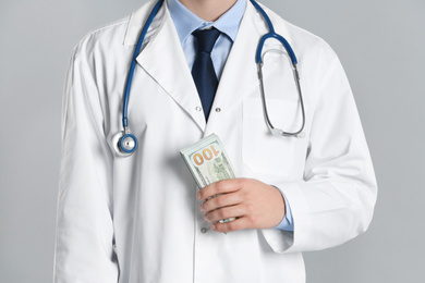 Doctor with bribe on grey background, closeup. Corruption in medicine