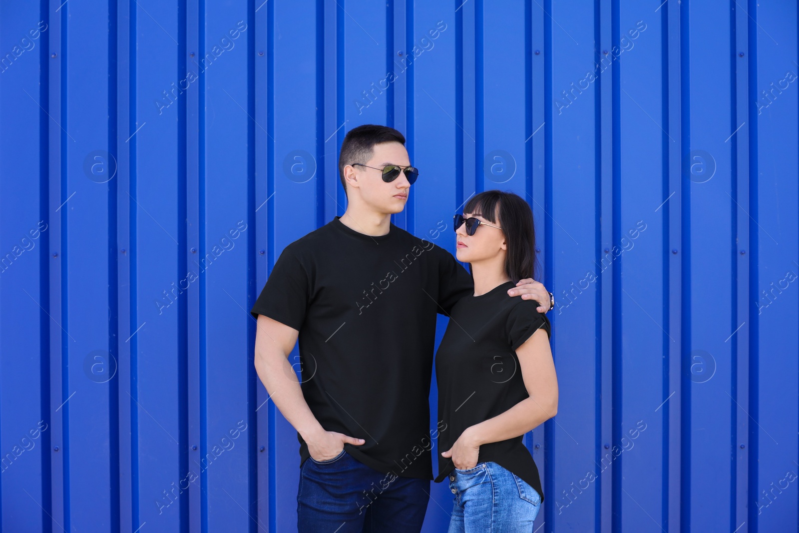 Photo of Young couple in black t-shirts near color wall. Mockup for design