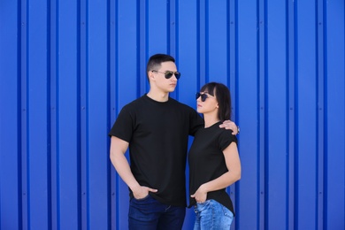 Young couple in black t-shirts near color wall. Mockup for design