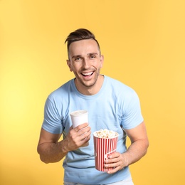 Man with popcorn and beverage during cinema show on color background