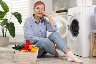 Photo of Smiling housewife with laundry near washing machine at home