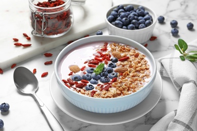 Smoothie bowl with goji berries and spoon on marble table