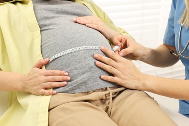 Photo of Pregnancy checkup. Doctor measuring patient's tummy in clinic, closeup