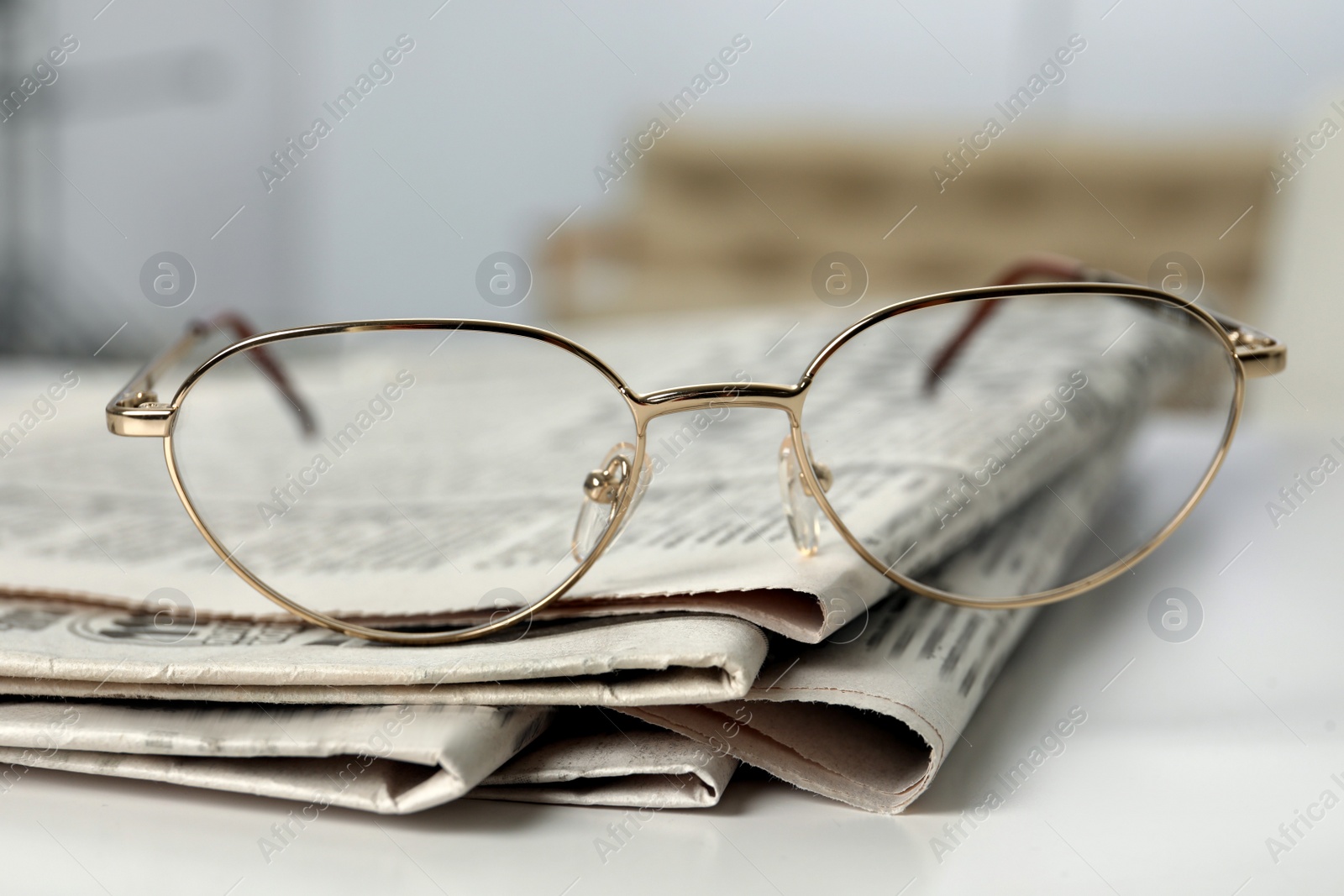 Photo of Stack of newspapers and glasses on white table indoors, closeup