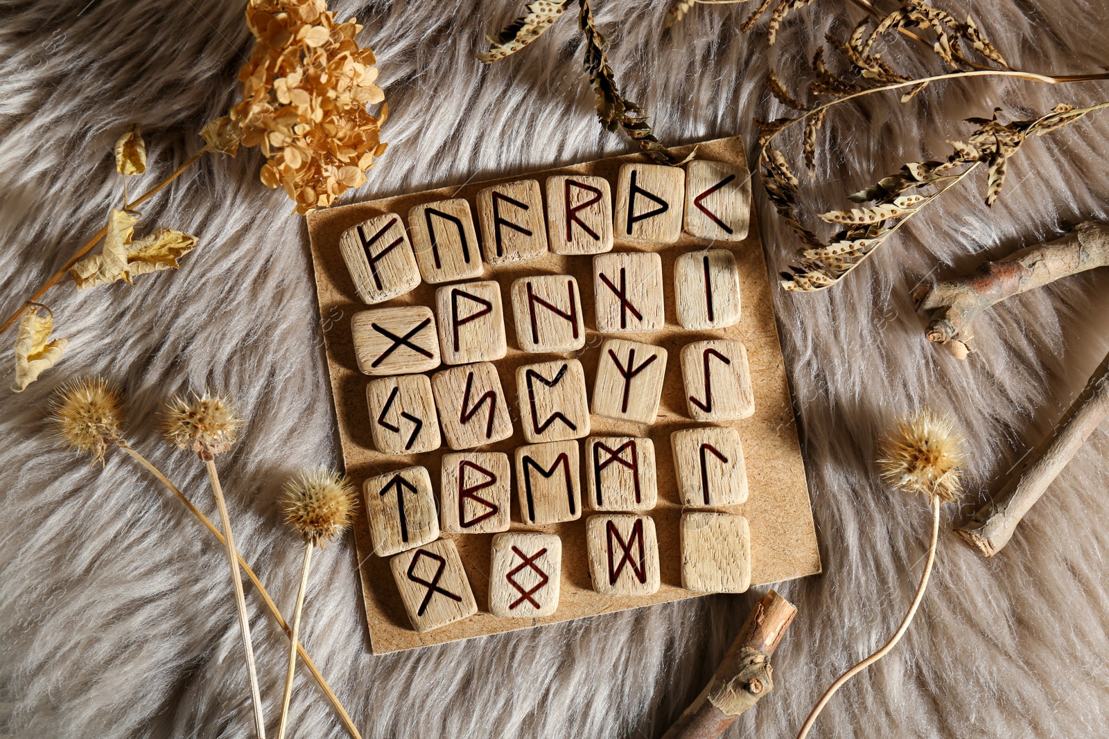 Photo of Many wooden runes and dried flowers on fur, flat lay