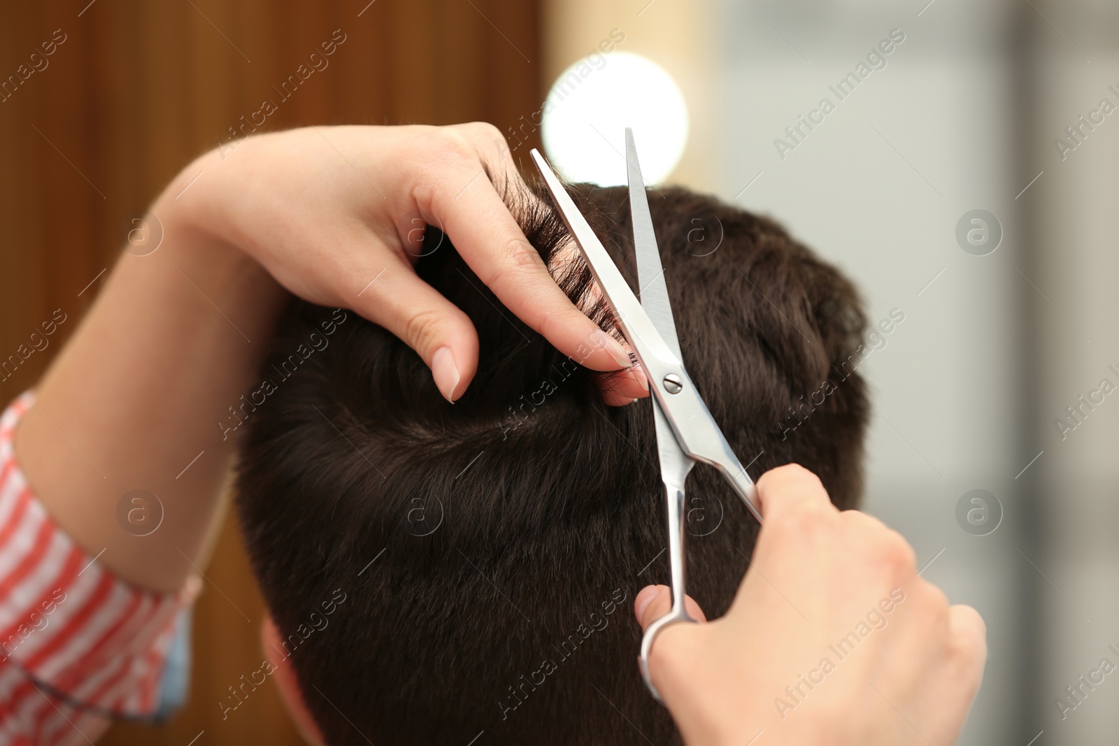 Photo of Barber making stylish haircut with professional scissors in beauty salon, closeup