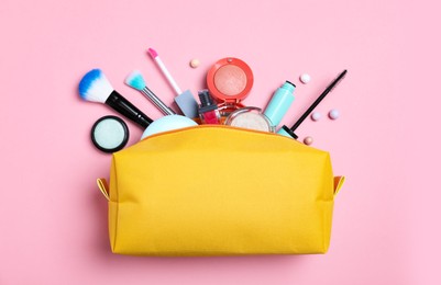 Photo of Cosmetic bag and makeup products with accessories on pink background, flat lay