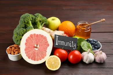 Photo of Card with word Immunity and fresh products on wooden table