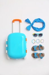 Photo of Composition with blue suitcase and child accessories on white background, top view. Summer vacation