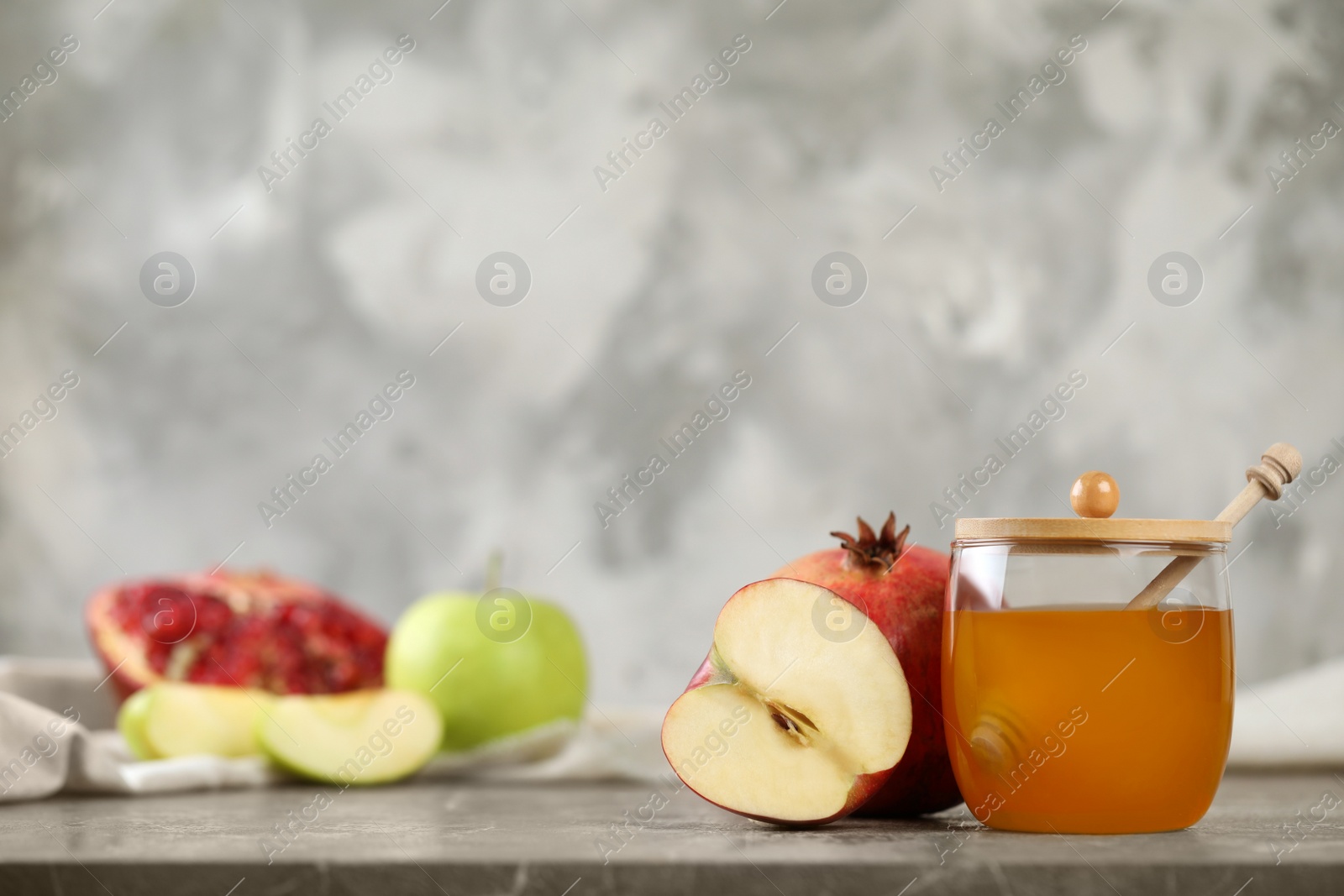 Photo of Honey, apples and pomegranate on marble table, space for text. Rosh Hashanah holiday