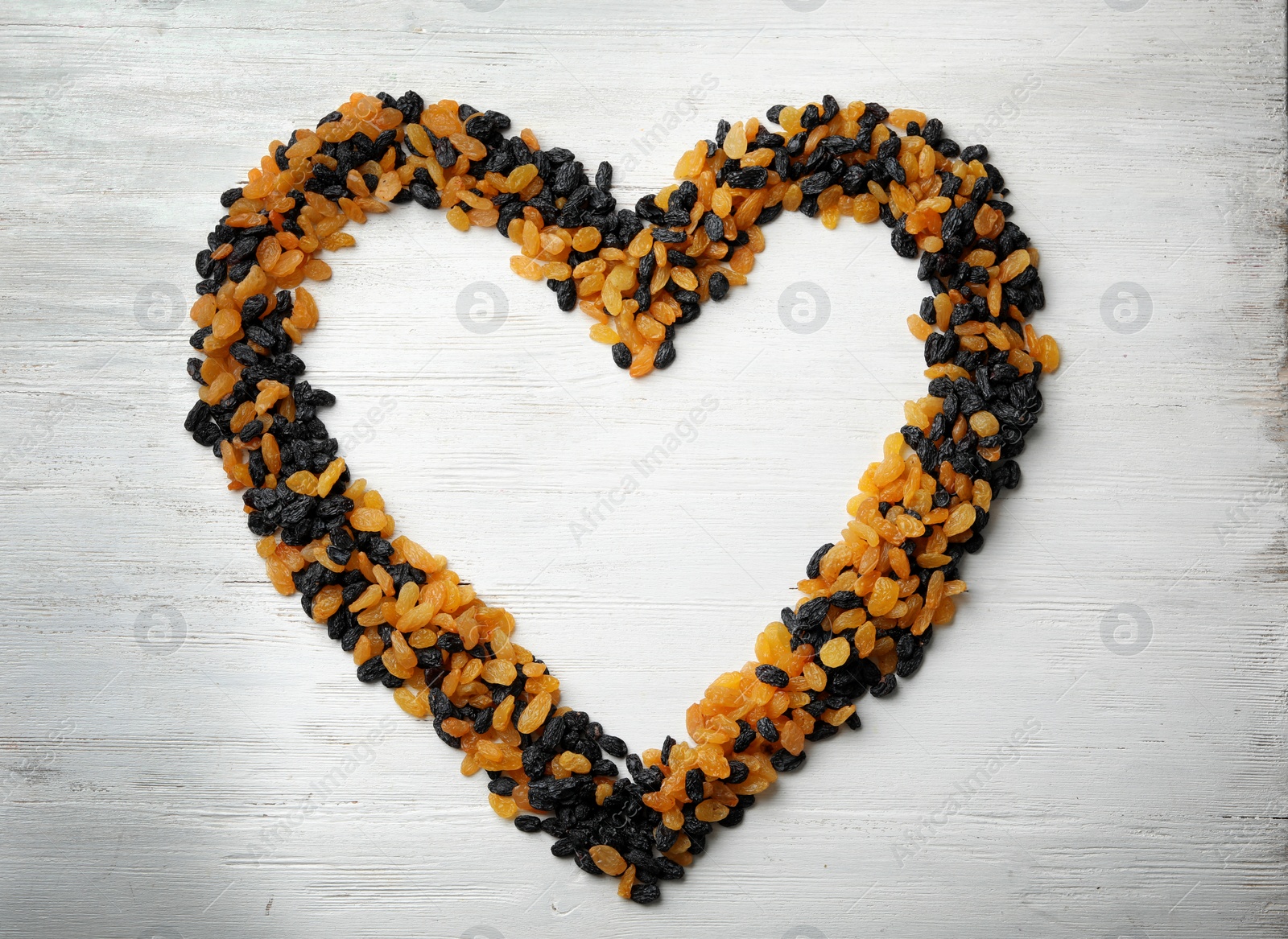 Photo of Frame made of raisins on wooden background, top view with space for text. Dried fruit as healthy snack