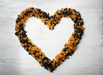 Frame made of raisins on wooden background, top view with space for text. Dried fruit as healthy snack