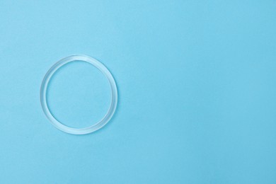 Photo of Diaphragm vaginal contraceptive ring on light blue background, top view. Space for text