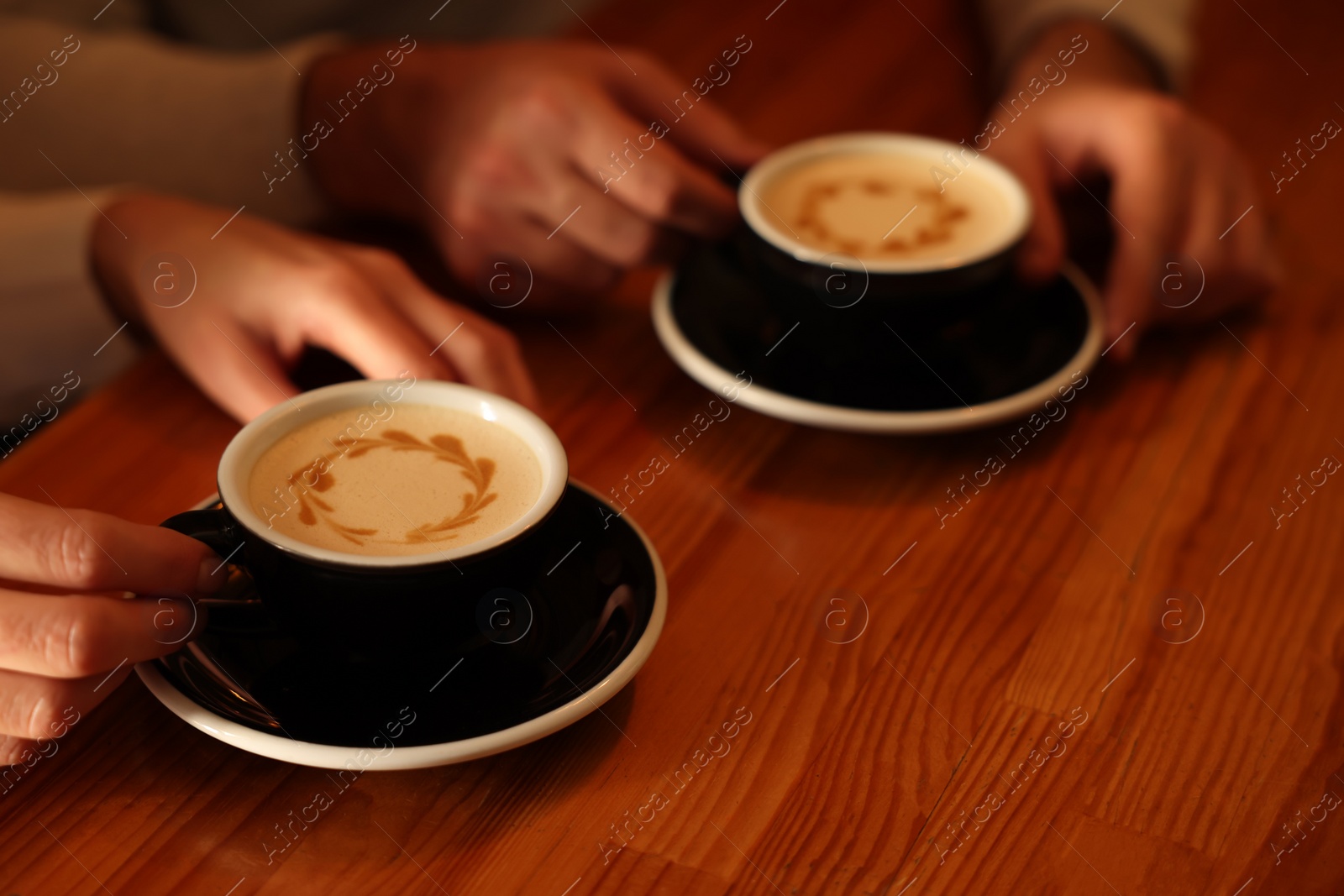 Photo of Couple with cups of aromatic coffee at wooden table, closeup