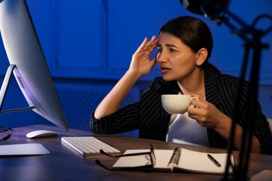 Photo of Tired overworked businesswoman drinking coffee at night in office