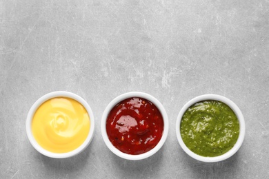 Set of different delicious sauces on grey table, top view. Space for text