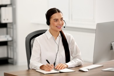 Hotline operator with headset and notebook working in office