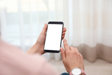 Photo of Woman holding smartphone with blank screen indoors, closeup of hands. Space for text