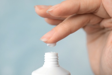 Woman applying hand cream on color background, closeup