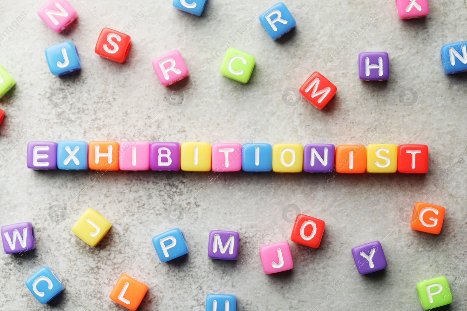 Photo of Word EXHIBITIONIST made with colorful cubes on light grey table, flat lay