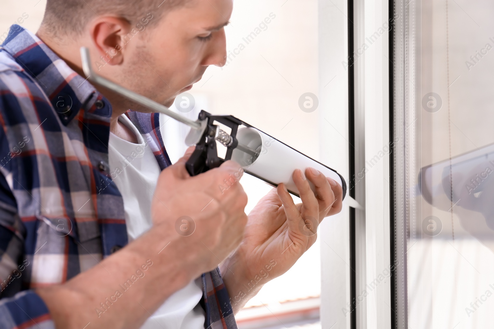 Photo of Construction worker sealing window with caulk indoors