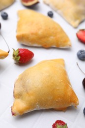 Delicious samosas and berries on white tiled table, closeup