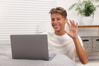 Photo of Happy young man having video chat via laptop indoors