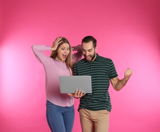 Photo of Emotional young people with laptop celebrating victory on color background