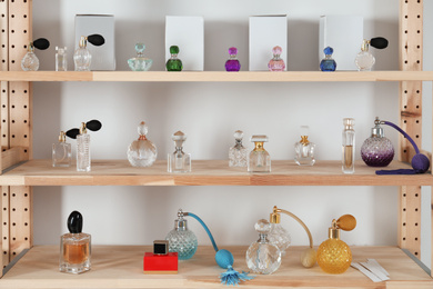 Different perfume bottles on wooden rack indoors