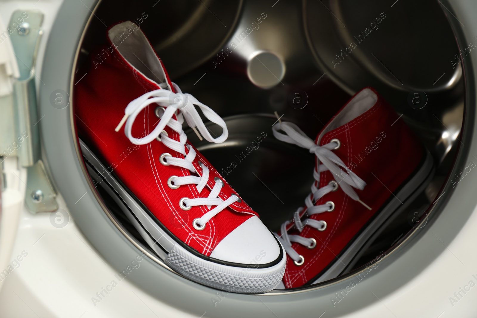 Photo of Clean sports shoes in washing machine drum, closeup