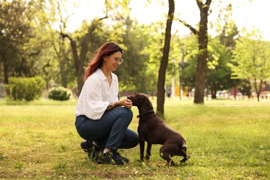 Photo of Woman with her cute German Shorthaired Pointer dog in park on spring day