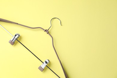 Empty hanger with clips on yellow background, top view. Space for text