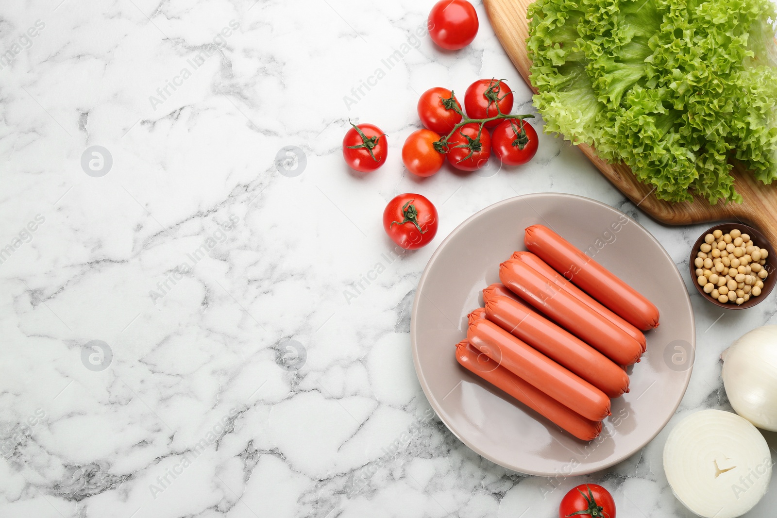Photo of Fresh raw vegetarian sausages, soybeans and vegetables on white marble table, flat lay. Space for text