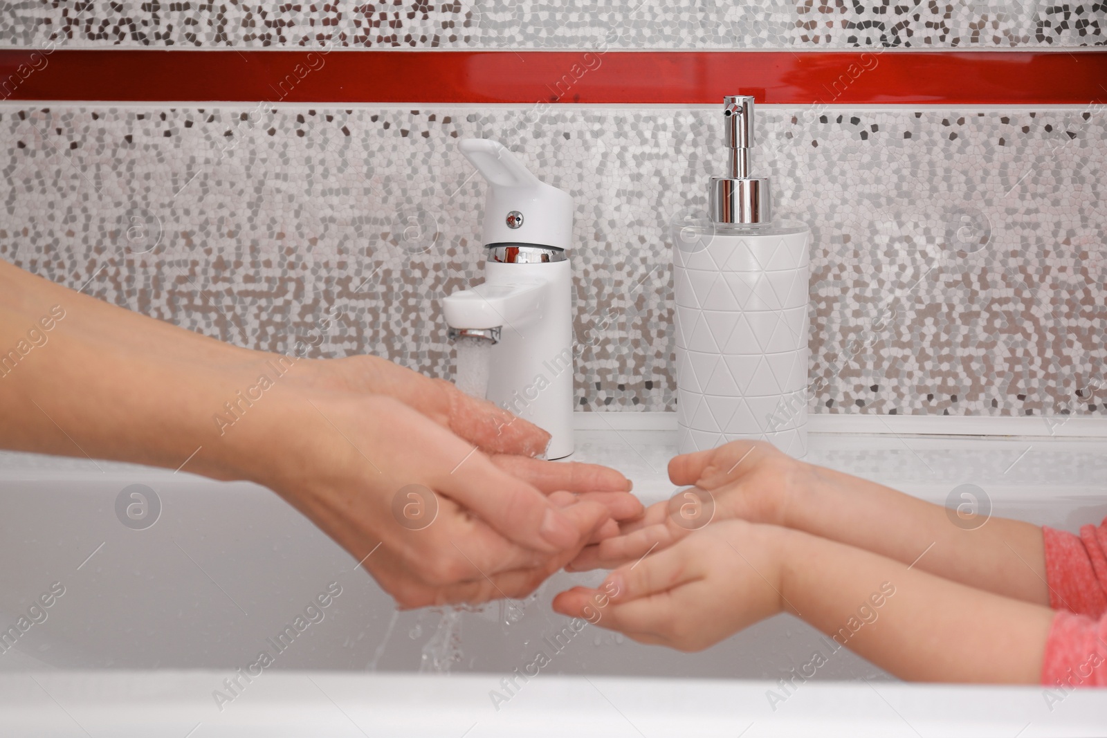 Photo of Mother and daughter washing hands in bathroom at home, closeup