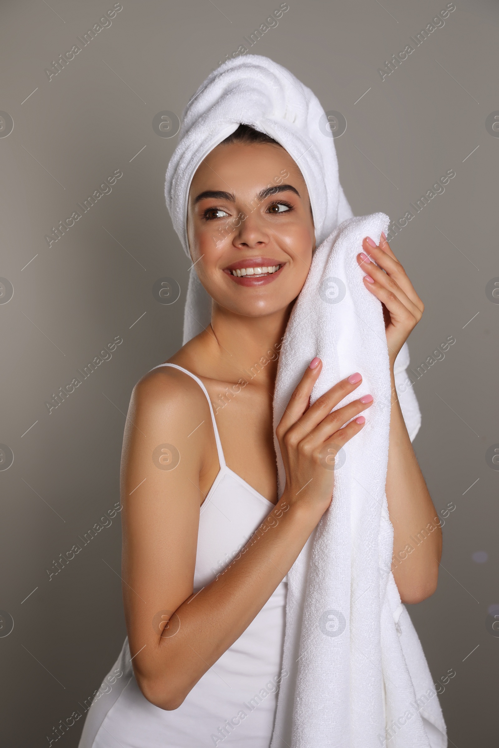 Photo of Beautiful young woman with towels on grey background