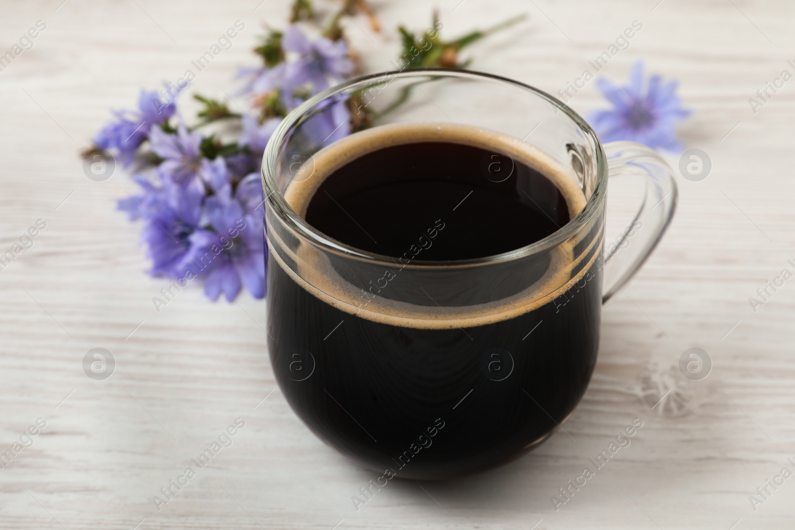 Photo of Glass cup of delicious chicory drink on white wooden table, closeup
