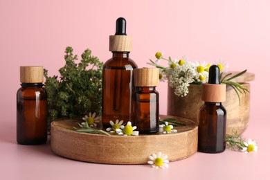 Photo of Aromatherapy. Different essential oils and flowers on pink background