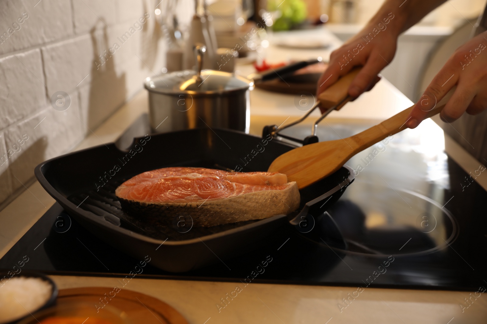 Photo of Man cooking fresh salmon steak in frying pan, closeup