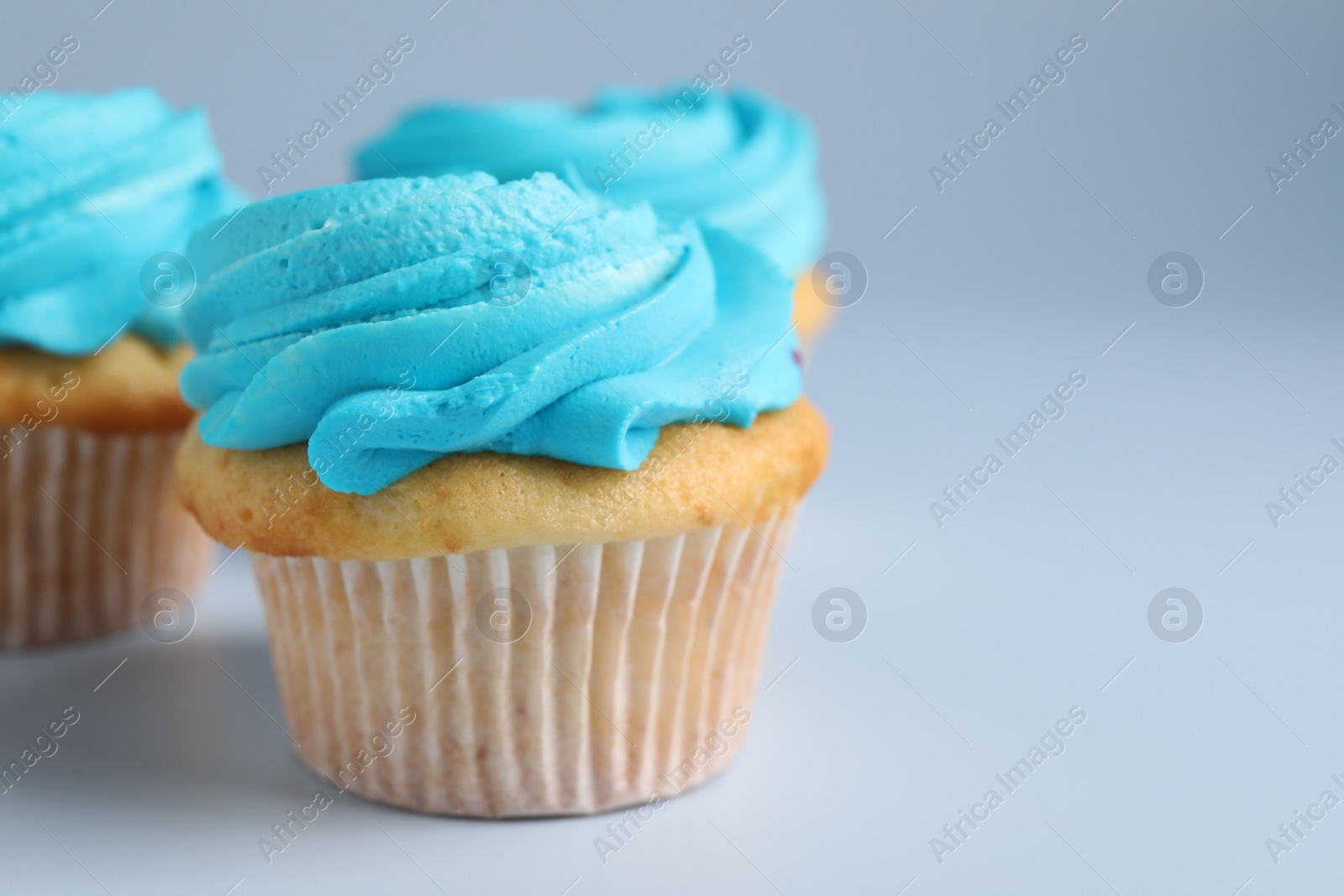 Photo of Delicious cupcakes with bright cream on light background, closeup. Space for text