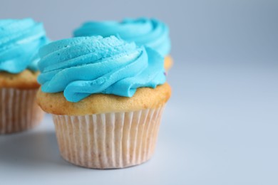 Photo of Delicious cupcakes with bright cream on light background, closeup. Space for text