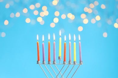 Photo of Hanukkah celebration. Menorah with burning candles on light blue background with blurred lights