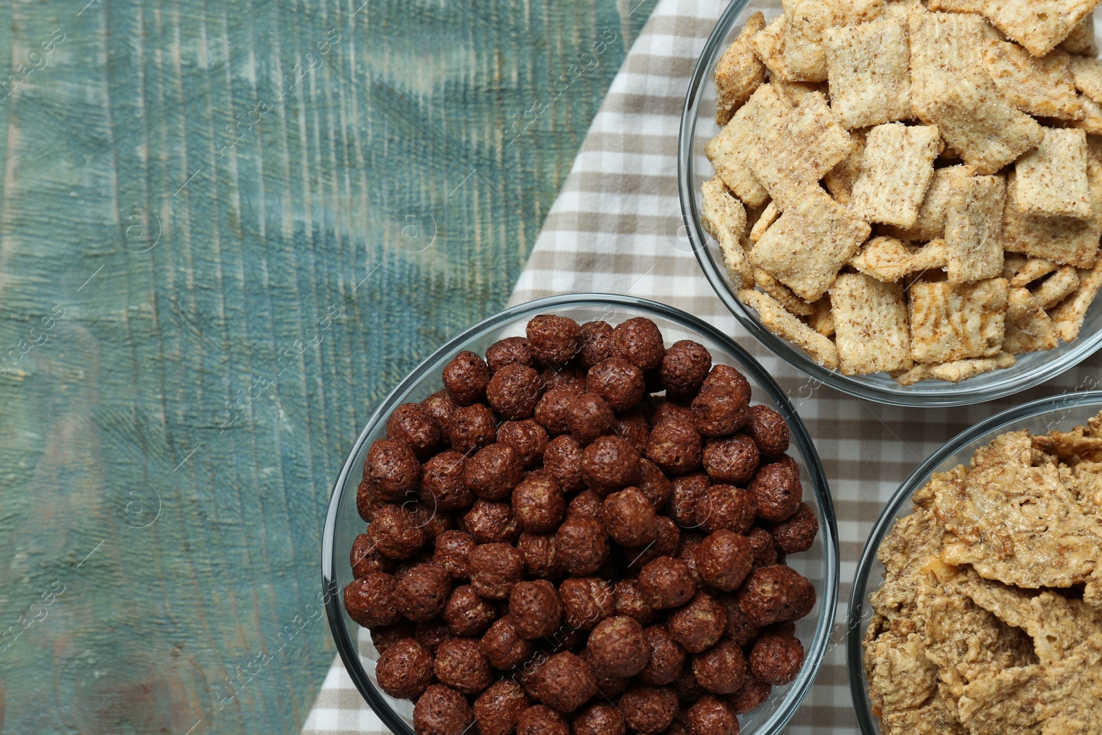 Photo of Different delicious breakfast cereals on blue wooden table, flat lay. Space for text