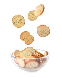 Delicious crispy rusks falling into bowl on white background
