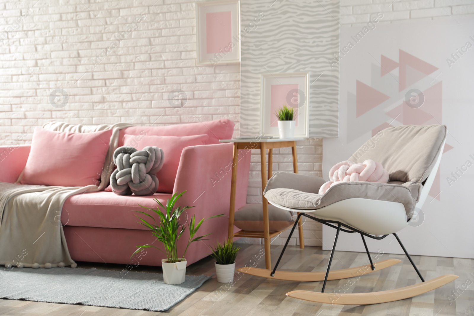 Photo of Stylish living room interior with sofa and rocking armchair near brick wall