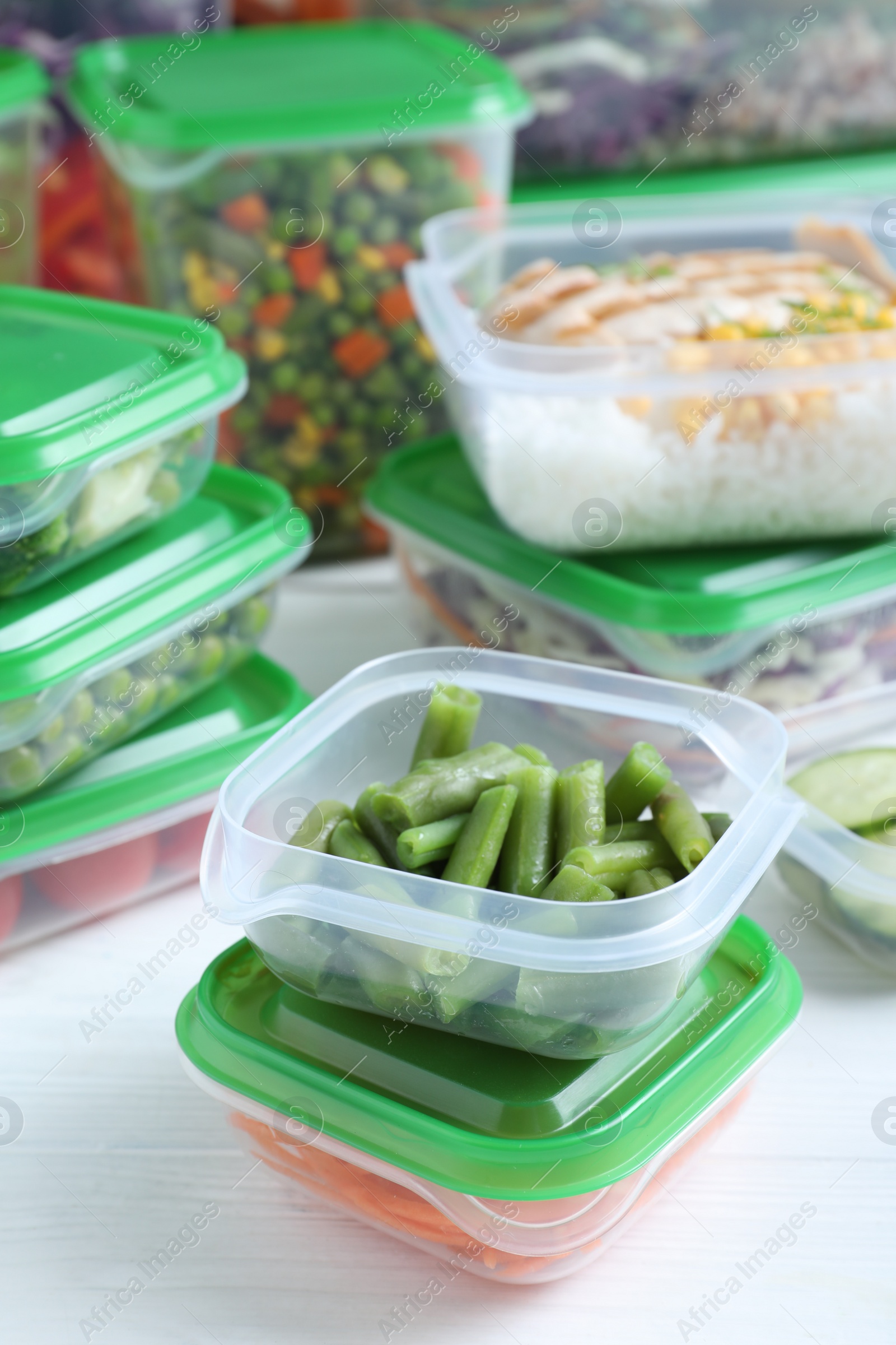 Photo of Set of plastic containers with fresh food on white wooden table