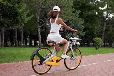 Beautiful young woman riding bicycle on lane outdoors