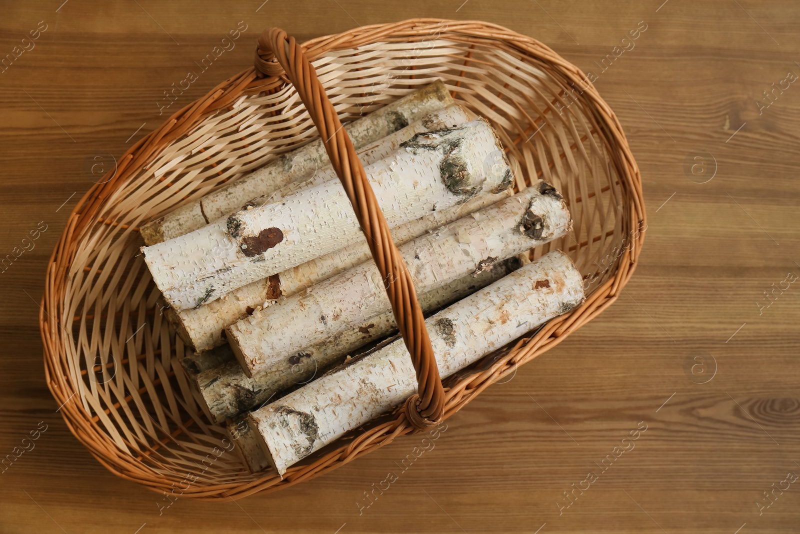 Photo of Wicker basket with firewood on floor indoors, top view