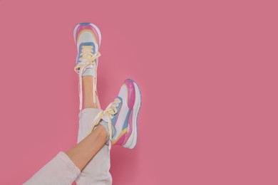 Photo of Woman wearing new stylish sneakers on pink background, closeup. Space for text
